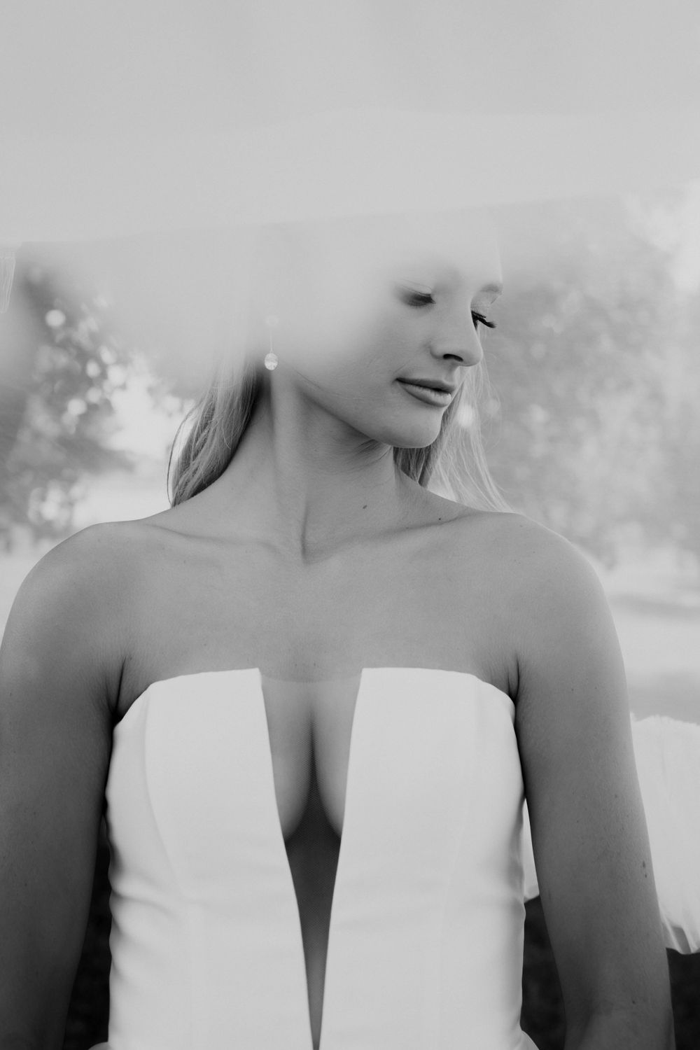 Artistic black and white portrait of bride in strapless wedding dress.