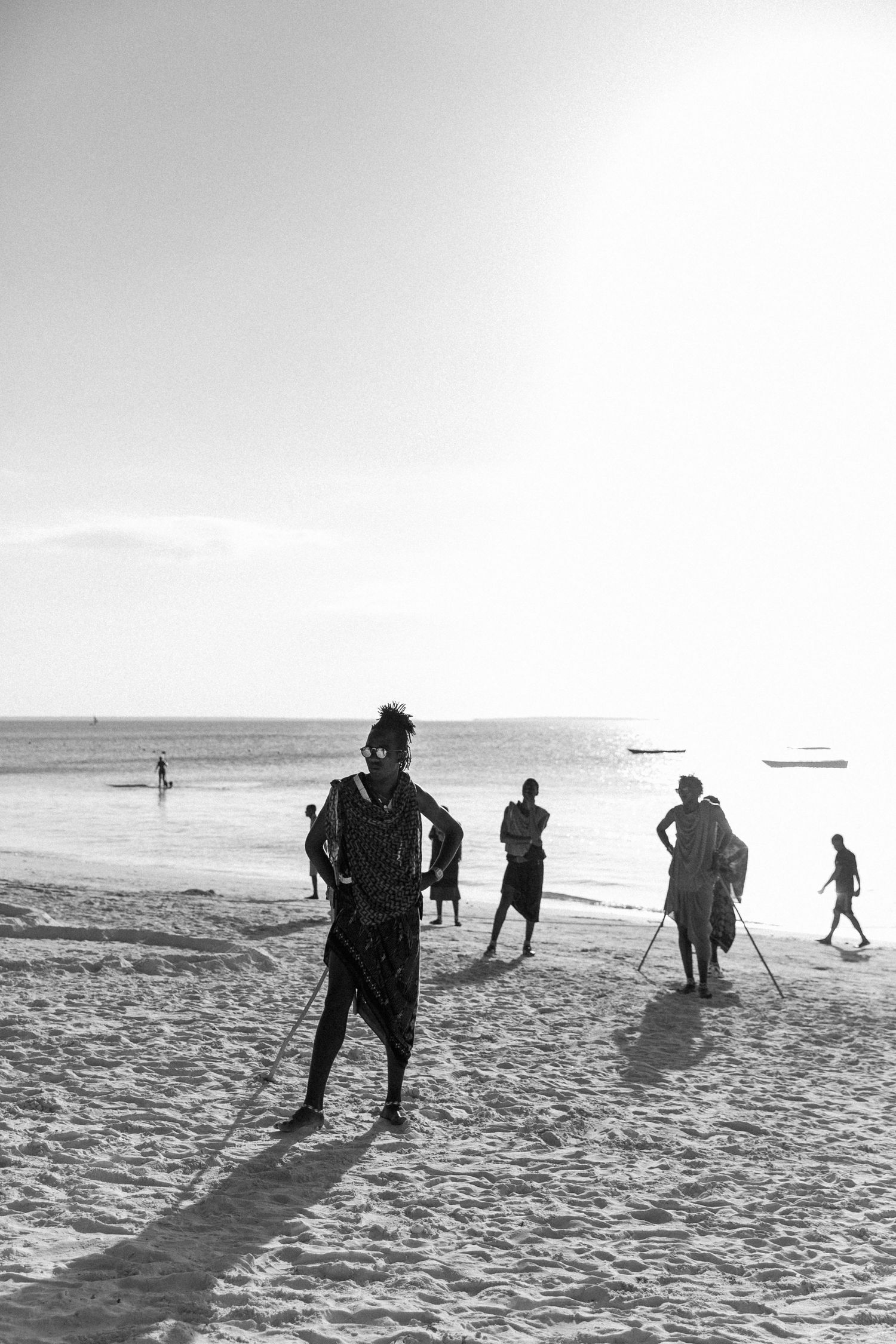 Masai men wearing traditional outfits and sunglasses standing on Nungwi beach in Zanzibar.