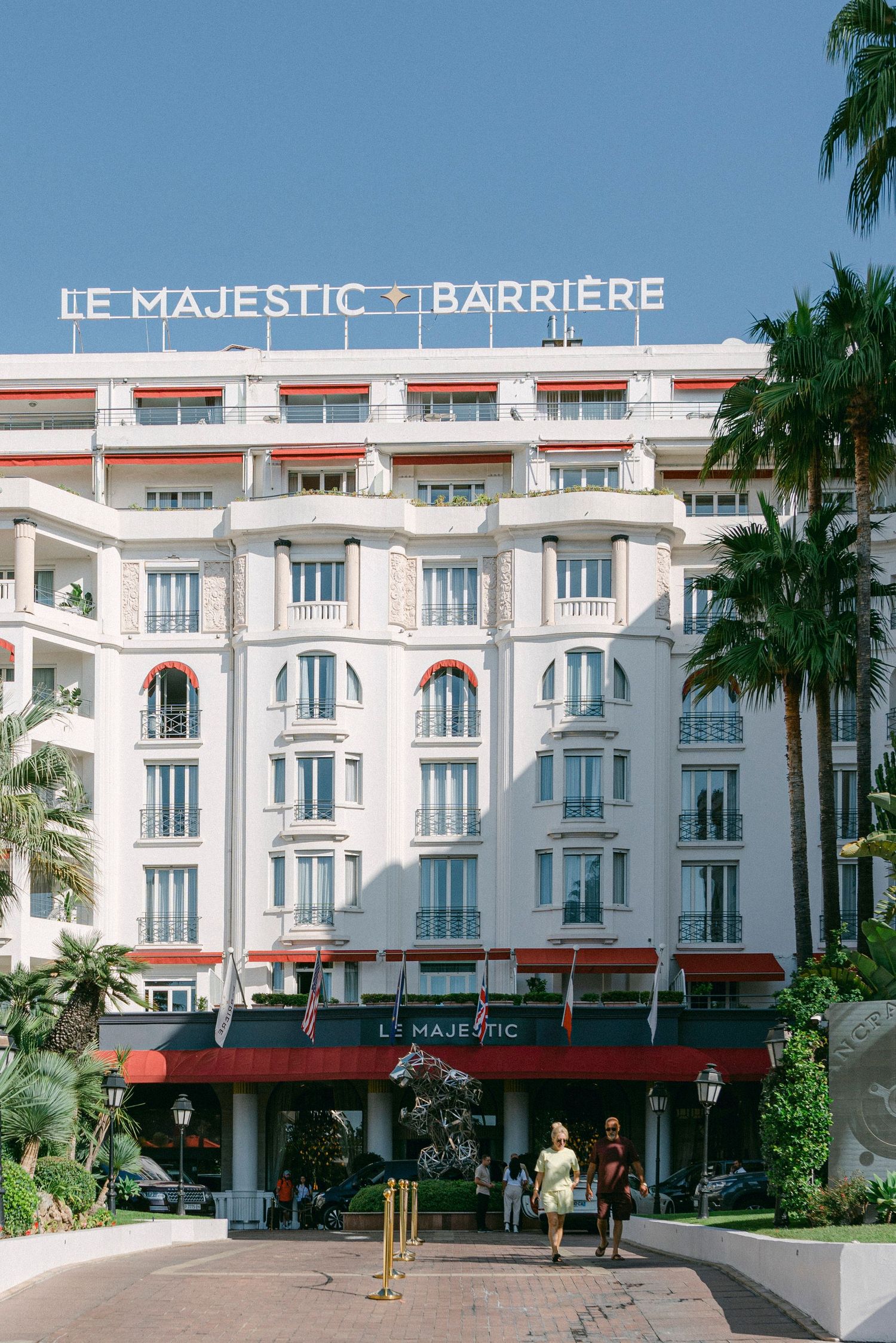 Majestic Barriere luxury hotel facade with palm trees in Cannes, France.
