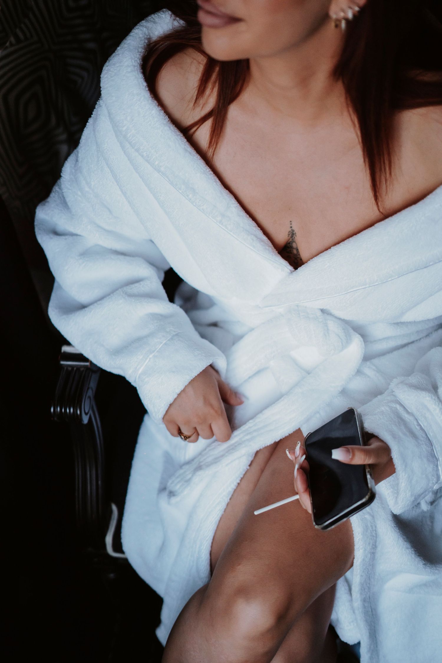 White plush bathrobe and phone on dark background.
