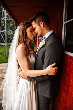A tender wedding moment captured against a rustic red wall.