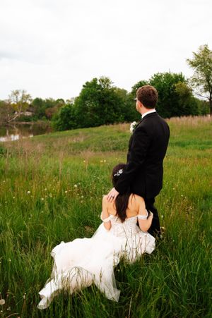 A wedding couple enjoys a quiet moment together in a wildflower meadow at sunset.
