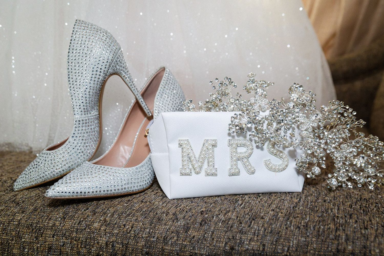 Crystal embellished stiletto heels next to MRS sign and baby's breath flowers.
