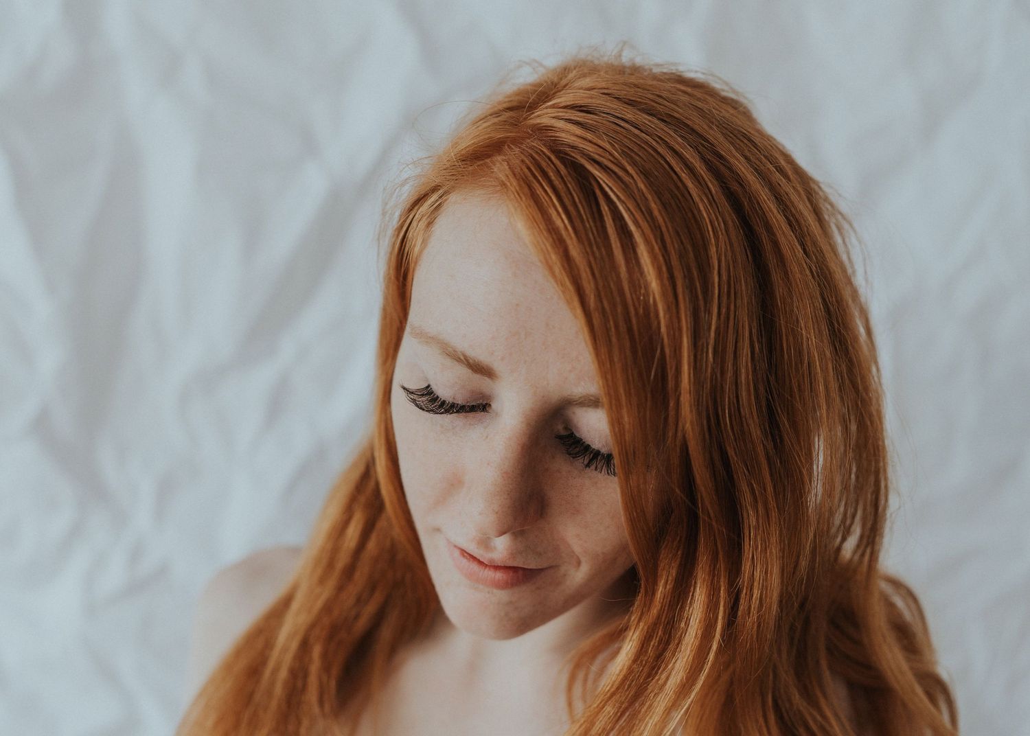 A redhead girl stands against a white paper backdrop