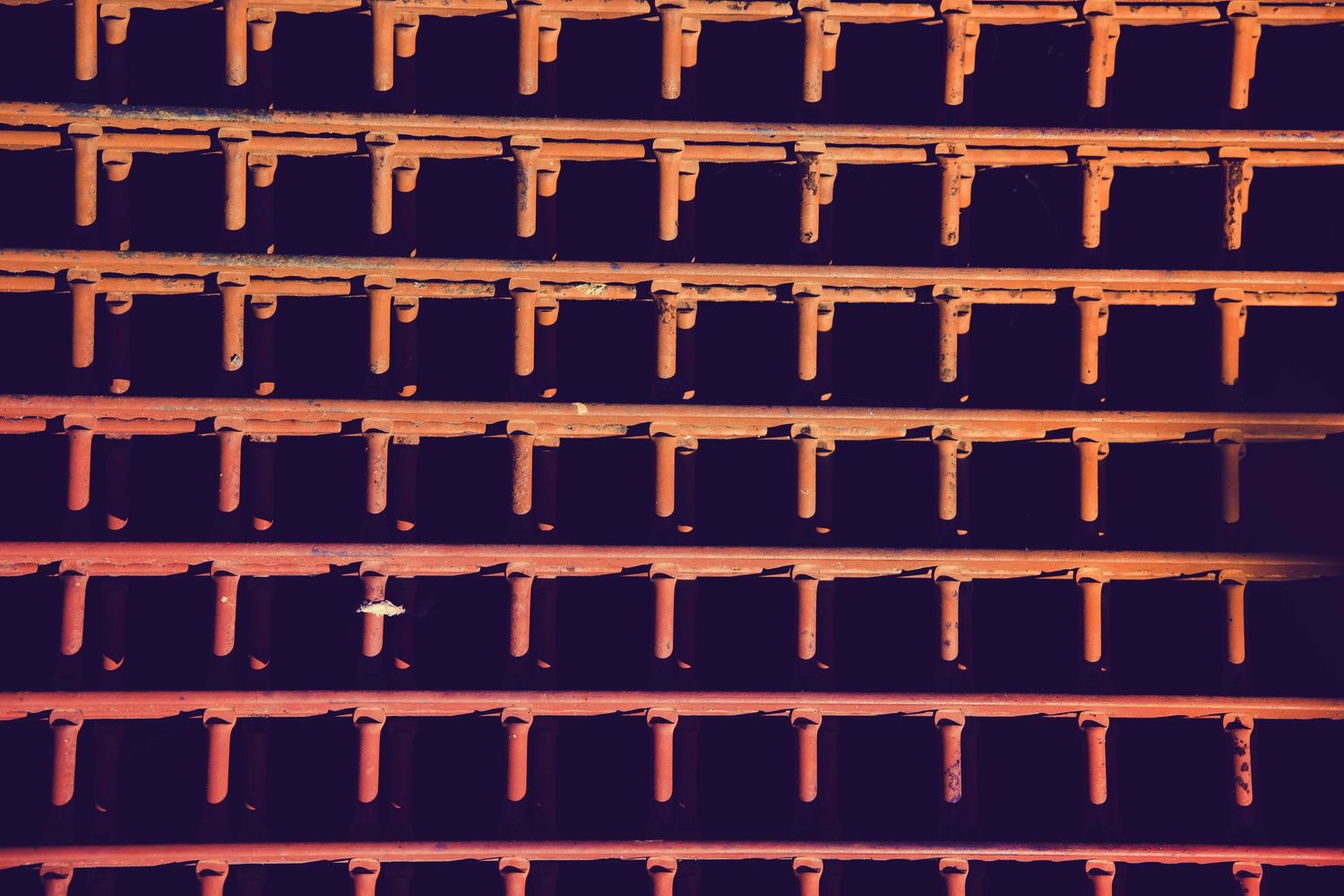 Geometric pattern of repeating orange brackets against dark background.