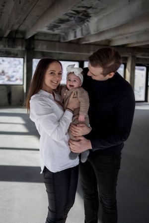 Family of three sharing happy moment together in sunlit industrial space.