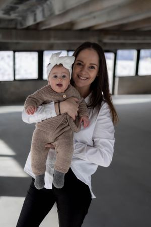 Parent and baby in coordinating outfits sharing joyful moment in bright indoor setting.