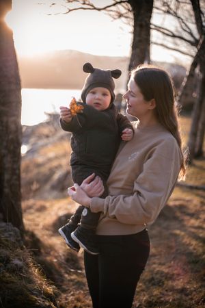 A heartwarming moment between parent and child in winter wear during sunset by a lake.