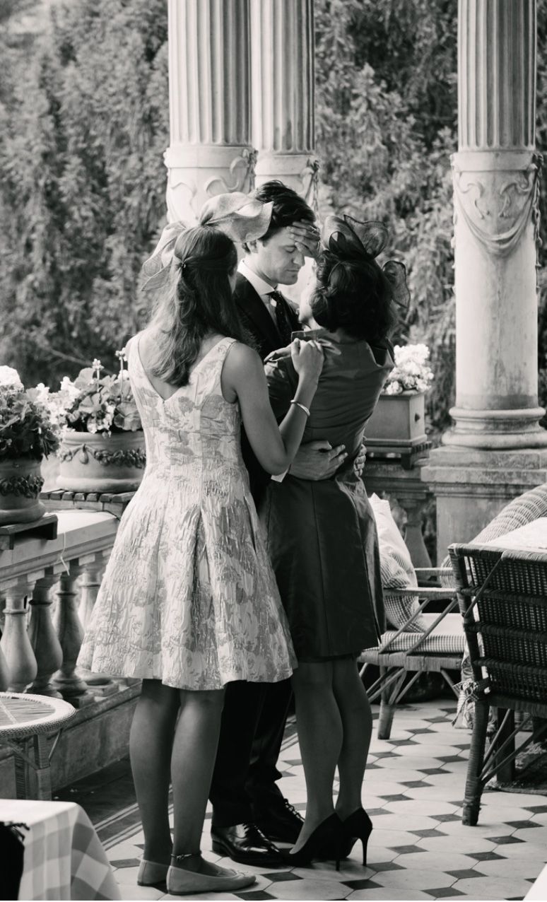 Three people dancing together in formal attire on an ornate patio with classical columns.