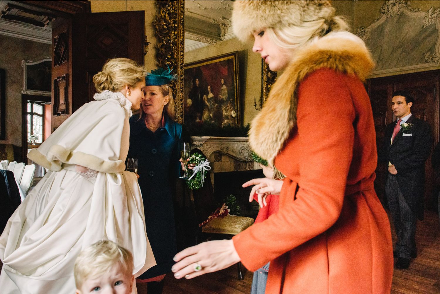 A bride in a flowing gown converses with guests at an indoor reception.