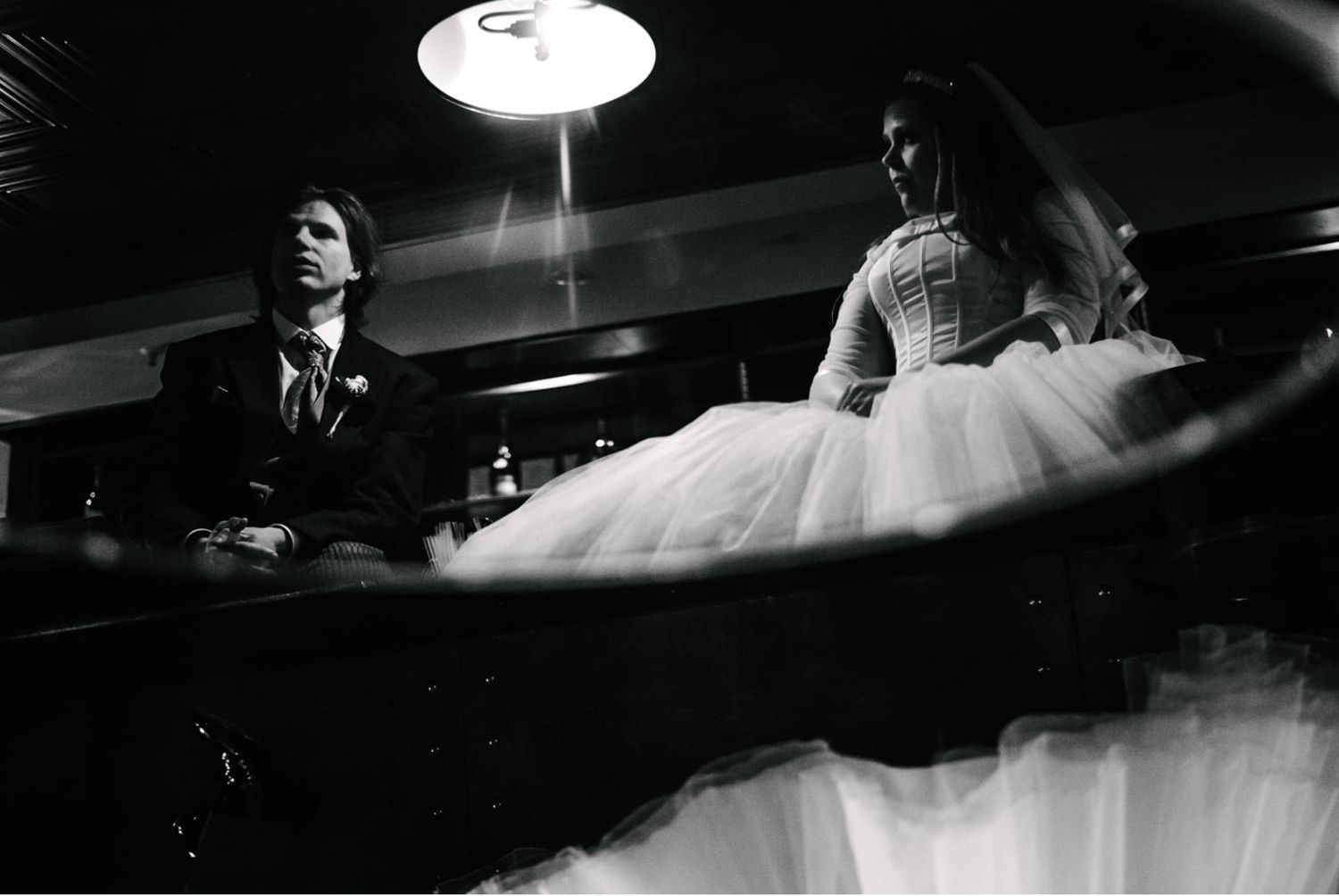 A couple at a bar counter captured in dramatic black and white lighting.