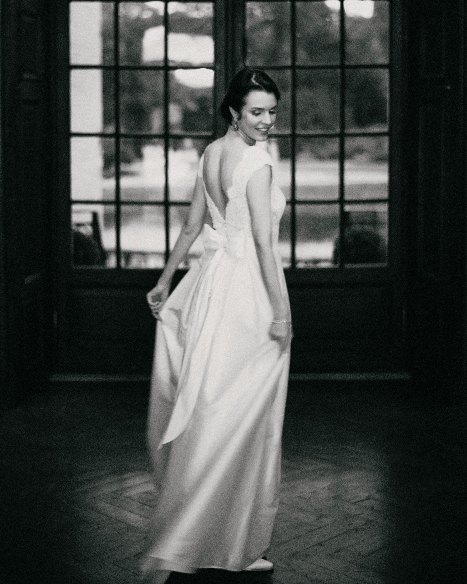 Artistic black and white photos of wedding dress details near large windows.