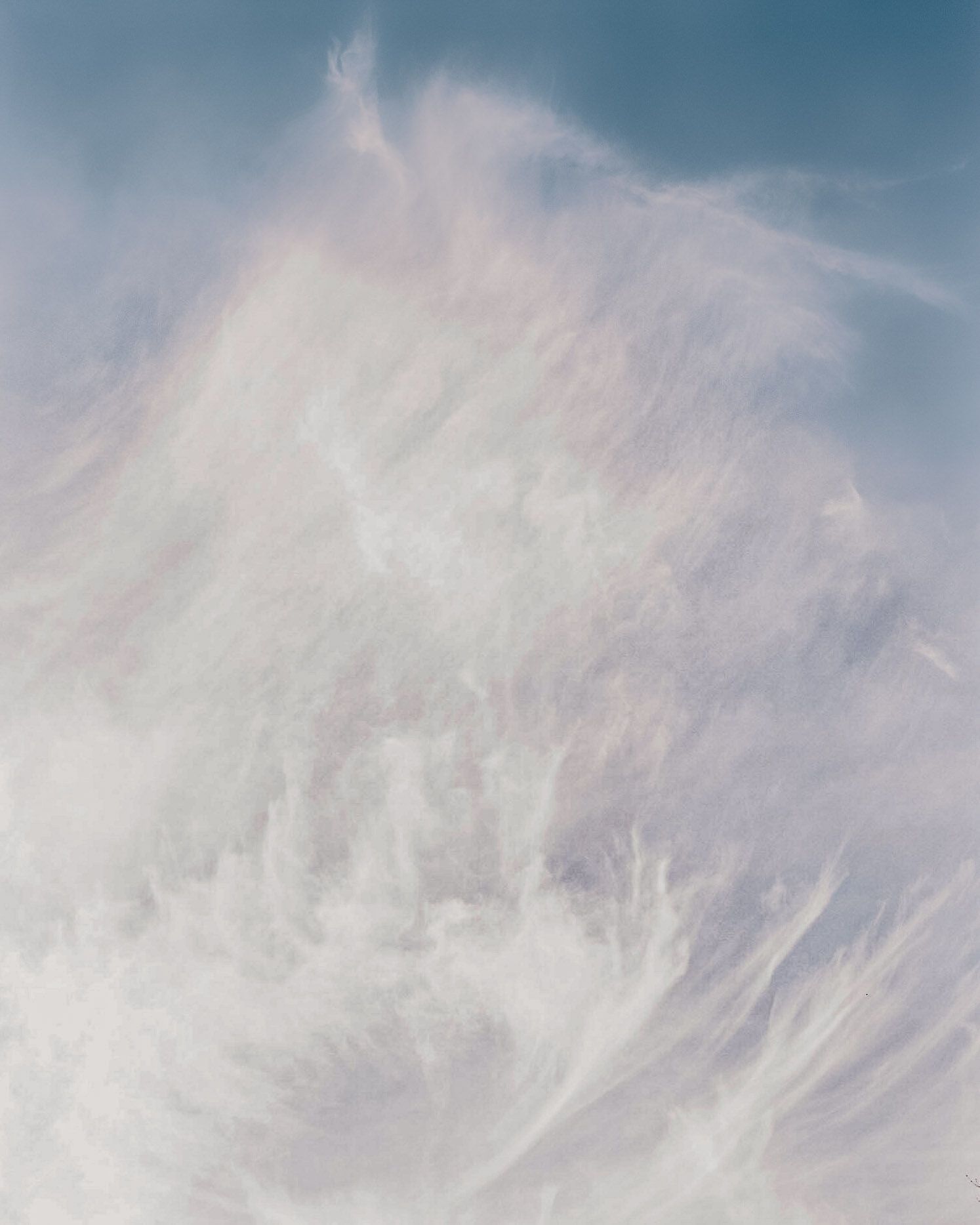 Ethereal white wispy clouds against a soft blue sky create a dreamy atmospheric background.