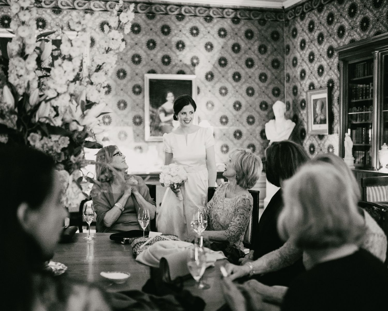 Vintage photograph of a social gathering in a wallpapered room with decorative plates.