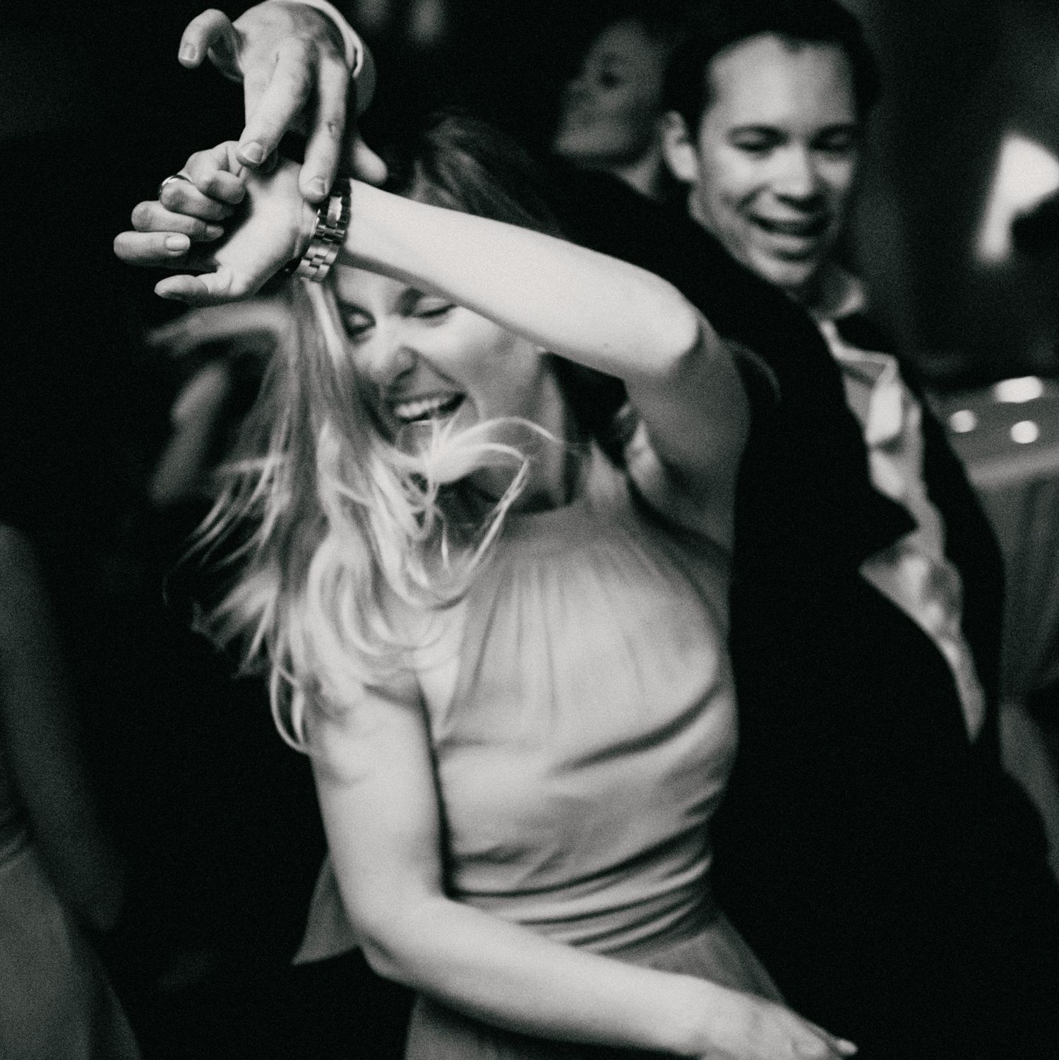 A joyful moment on the dance floor captured in black and white as a woman dances with carefree enthusiasm.