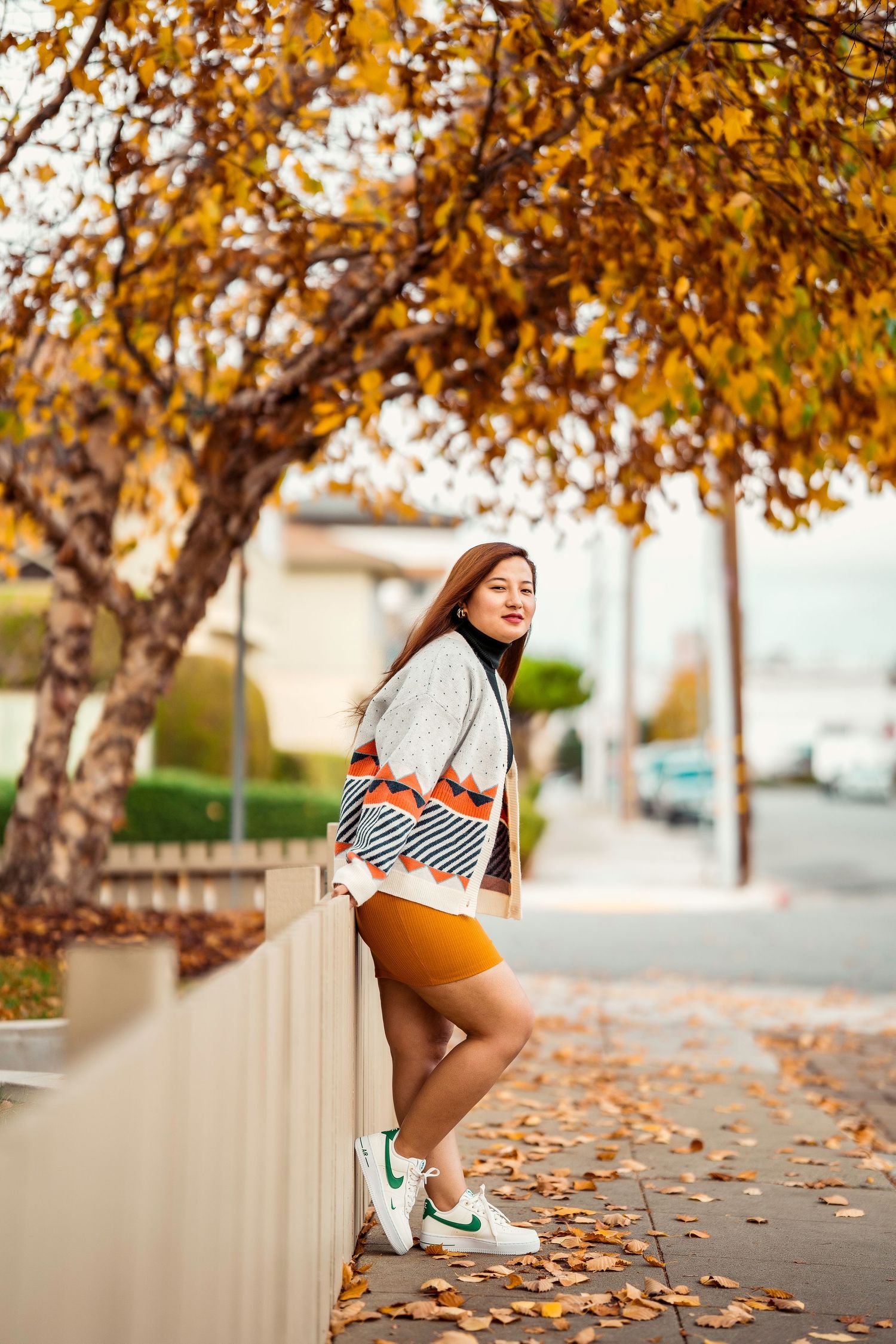 Stylish fall outfit photography with geometric pattern cardigan against autumn street scene.