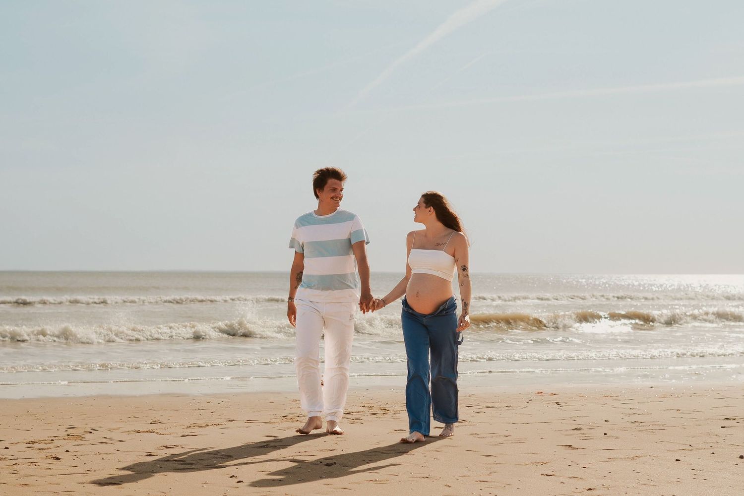 Couple walking together along a peaceful beach shoreline.
