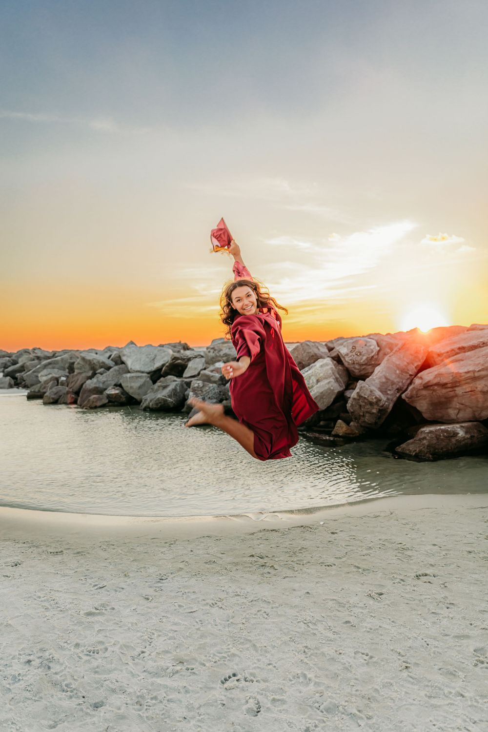 Dynamic sunset beach photos with flowing red dress against rocky coastal background.