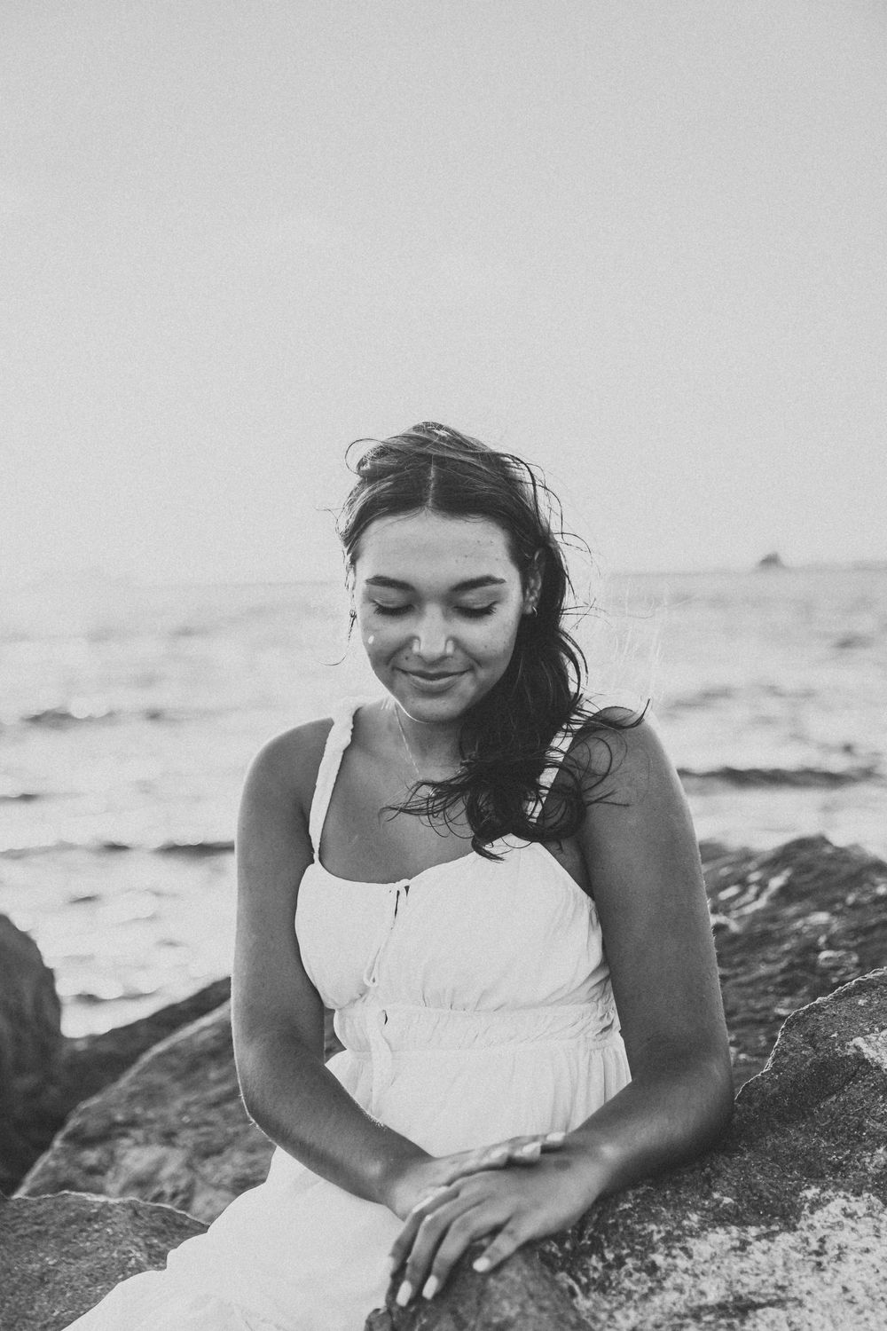 Black and white beach portraits on rocky shore with natural lighting and candid expressions.