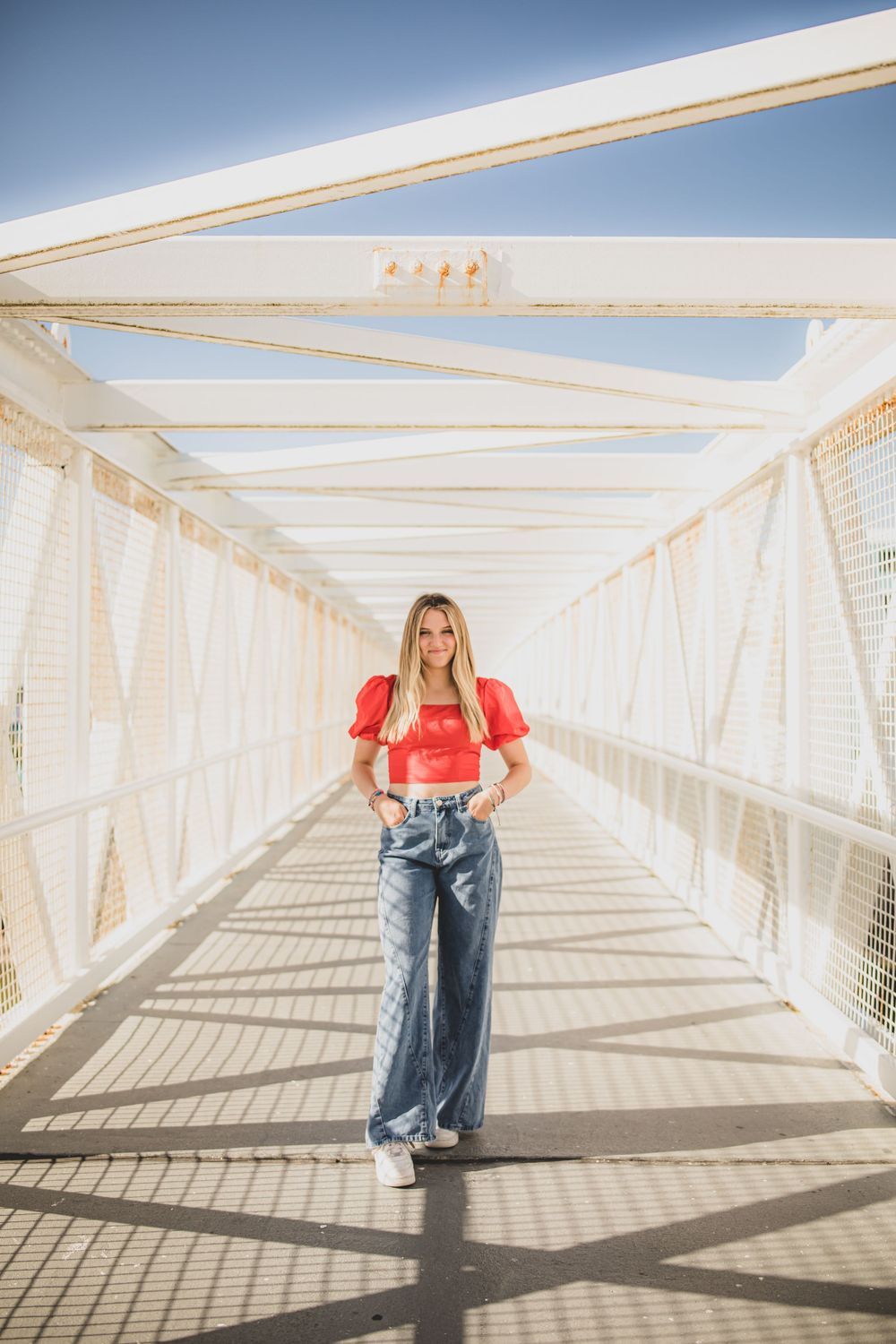A sequence of poses along a bright white covered walkway with geometric shadows.