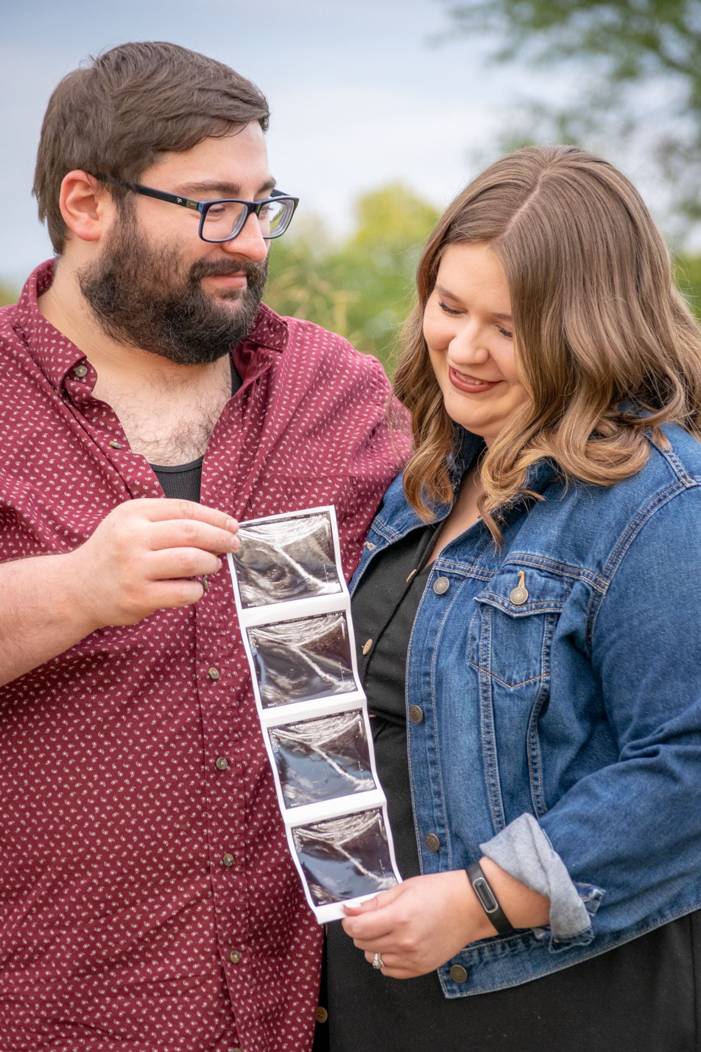 Baby Announcement Portrait Session. Dad holds ultrasound and smiles at mom. Mom smiles at ultrasound photos.