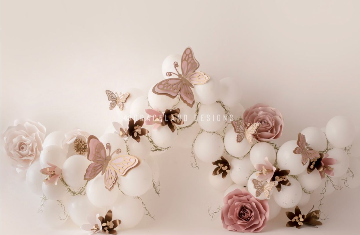 Delicate vintage arrangement of dusty pink roses and white orchids with rose gold butterflies on light beige background.