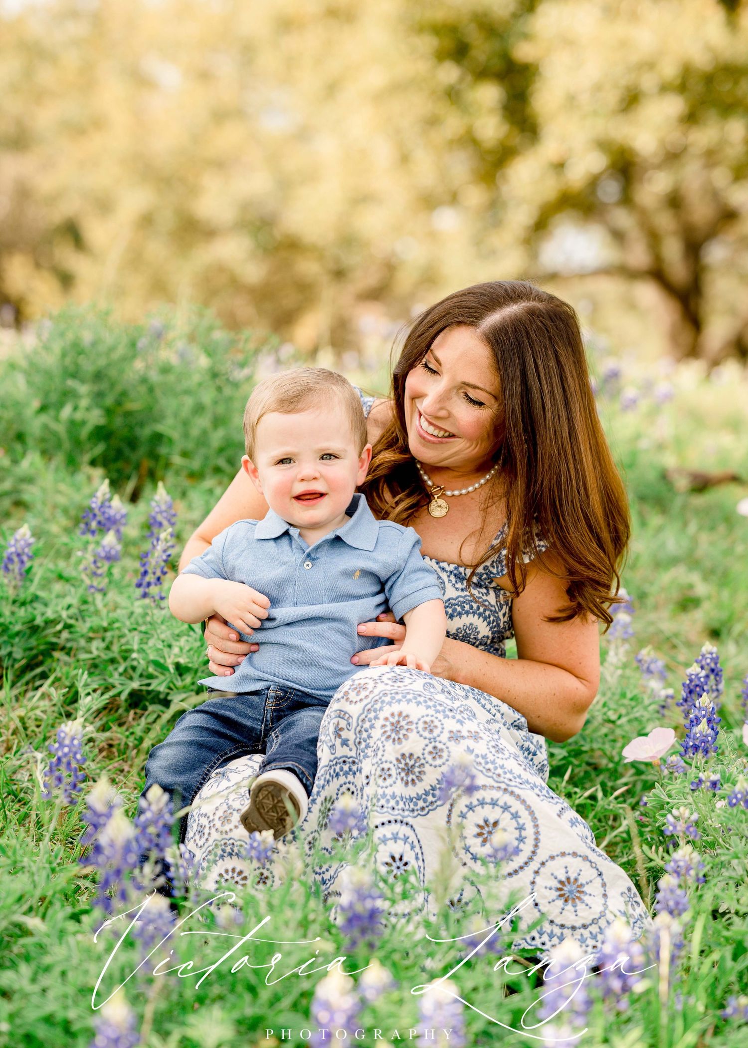 Mother and toddler sitting among purple wildflowers during spring photoshoot.