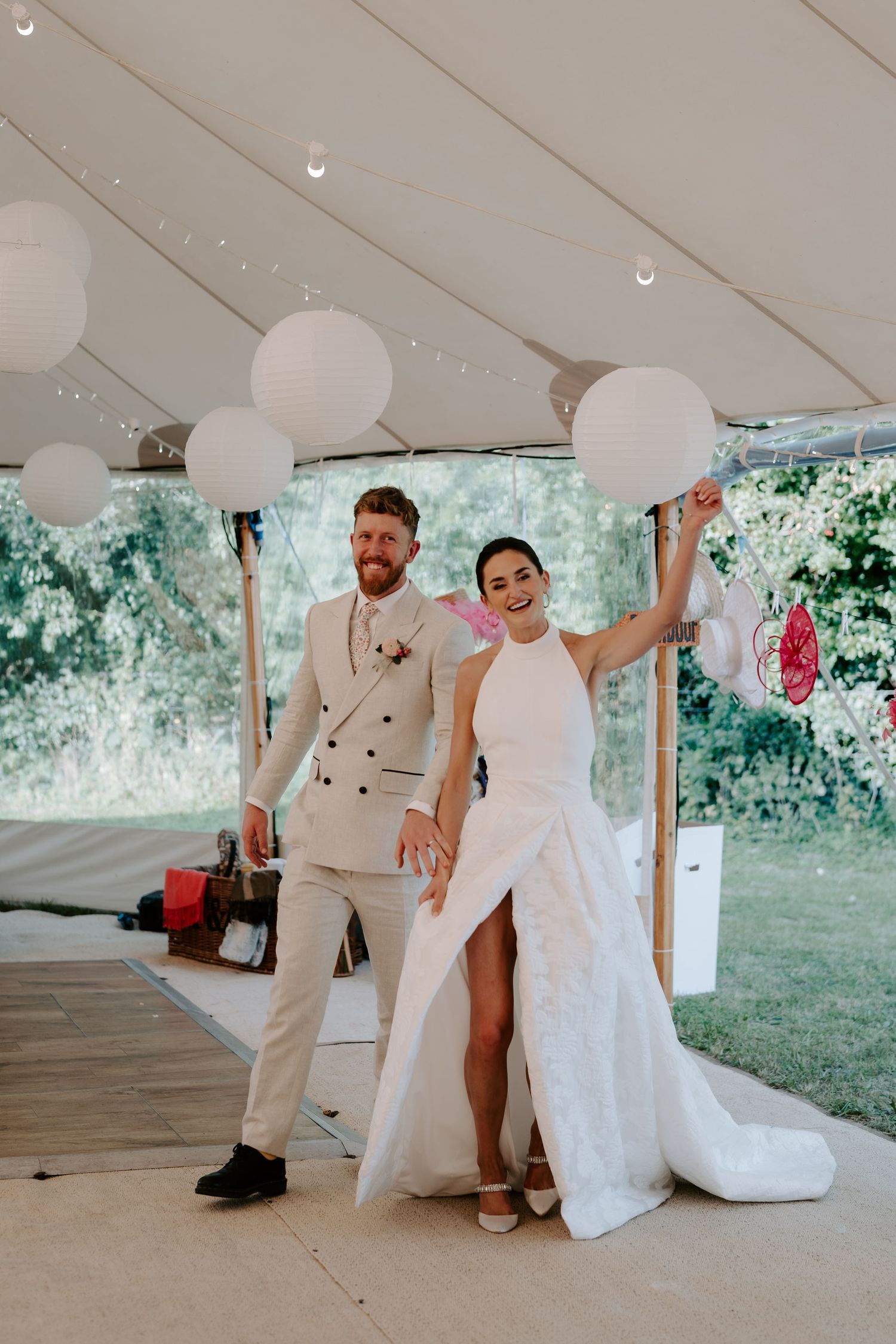 bride and groom waving while making their entrance into marquee for their wedding meal in islip in Oxfordshire