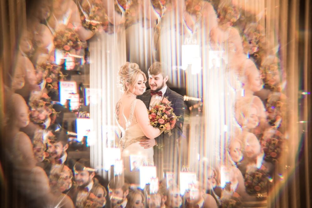 A romantic wedding photo captured through a creative circular frame with soft pink floral decorations.