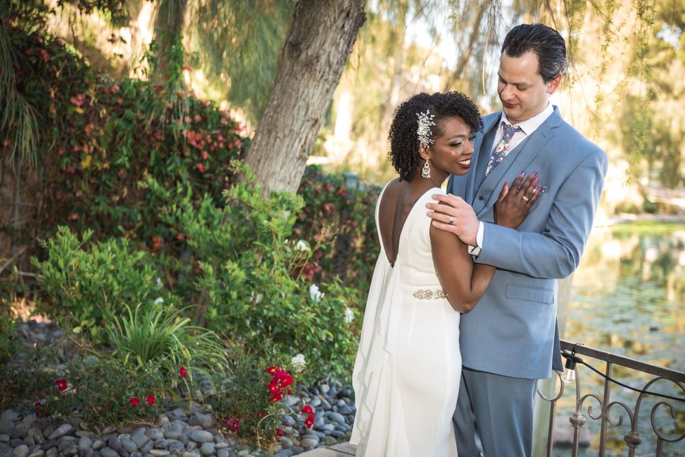 An intimate wedding moment captured in a lush garden setting with blooming red flowers.