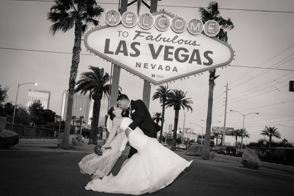 Black and white photo of newlyweds dancing beneath the iconic Las Vegas welcome sign.