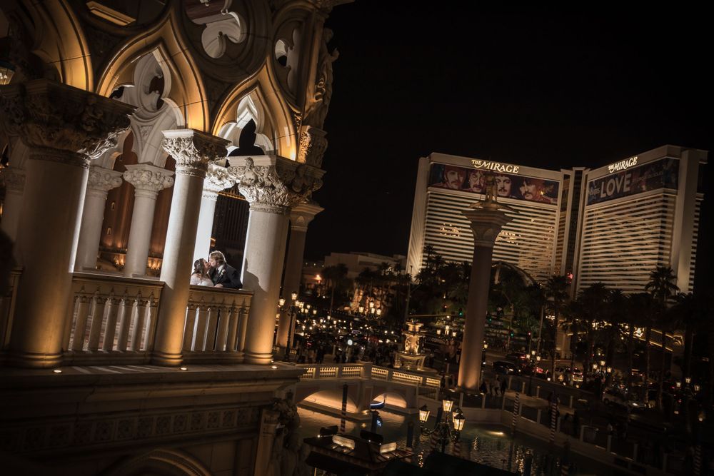 An elegant wedding photo taken at night with illuminated architecture and the Las Vegas strip in view.