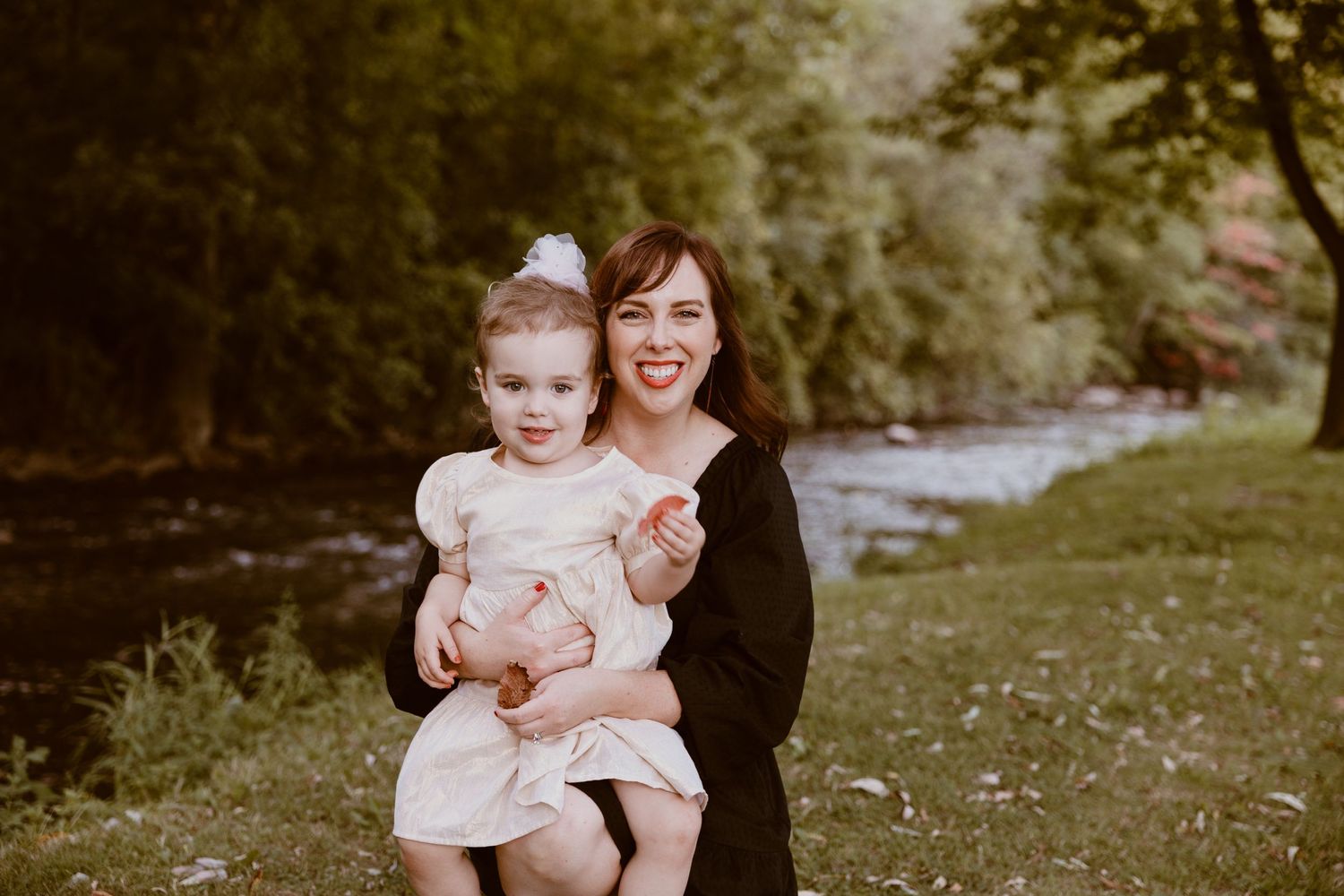 Family portrait taken by a stream in nature showing tender expressions.
