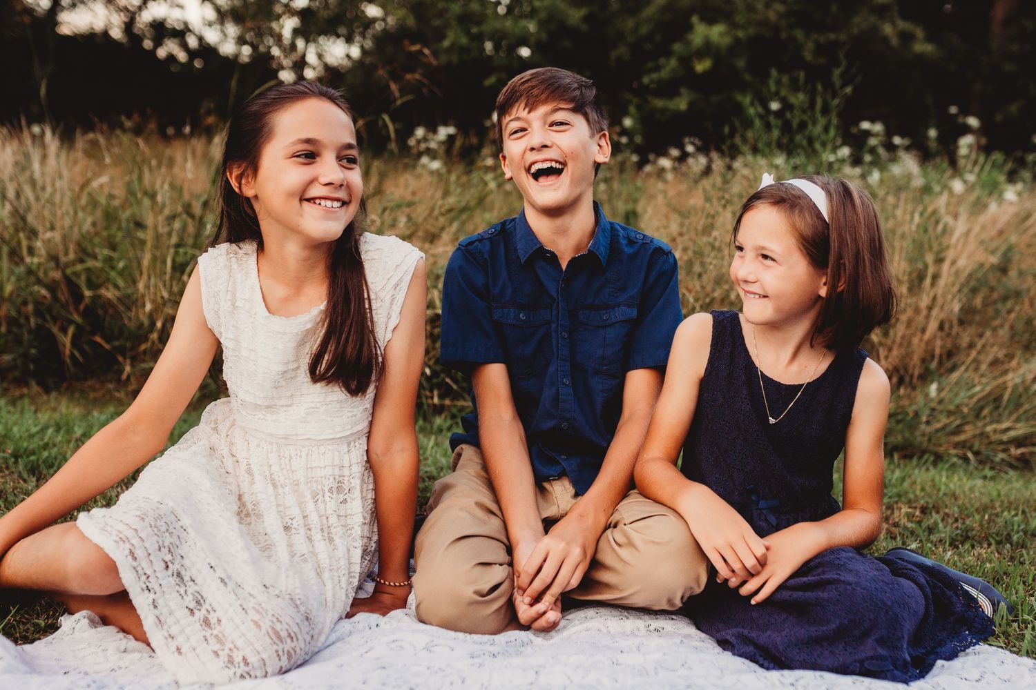 Brother and sisters laughing with each other in a field
