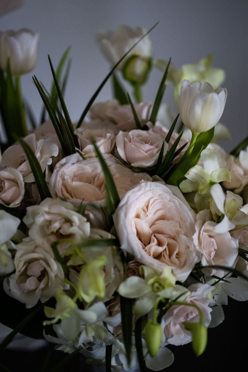 Elegant floral arrangement featuring blush roses and white orchids with green accents.