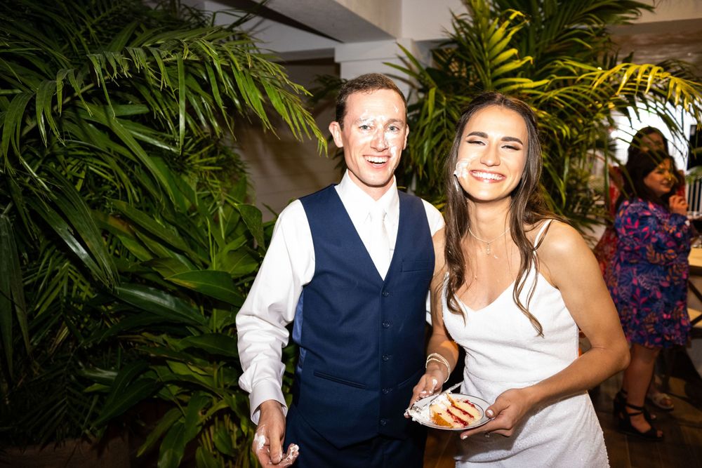 A couple celebrates at their wedding reception surrounded by tropical palm decorations.