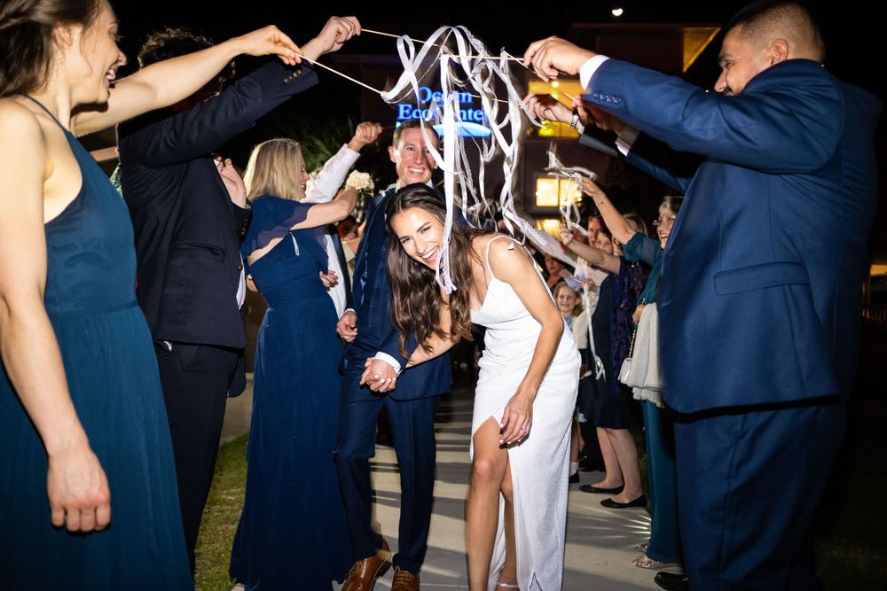 Wedding party creates a sparkler tunnel at night for celebration.