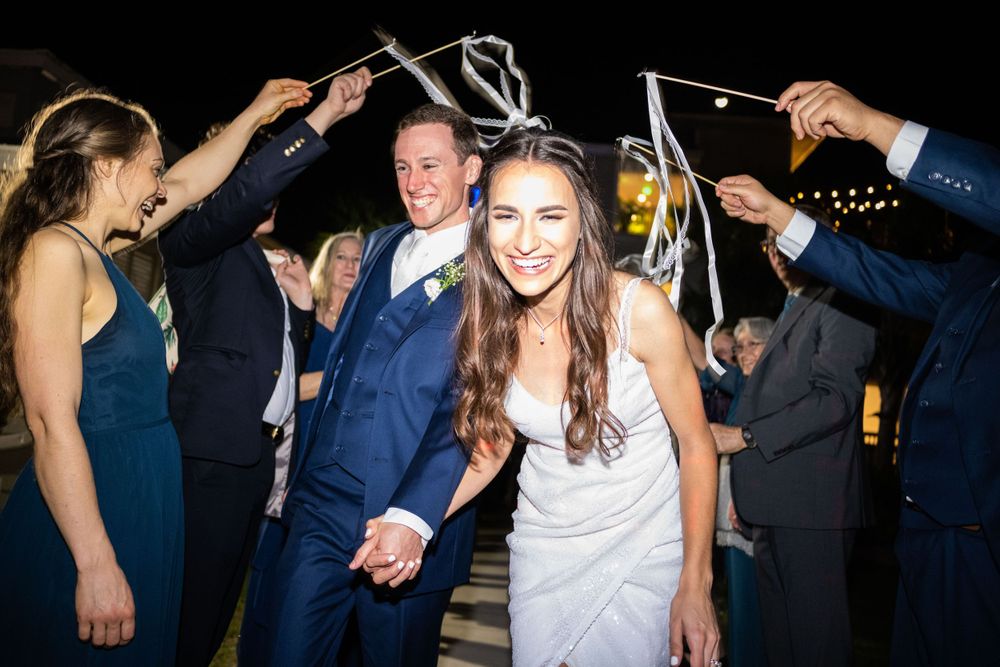 Wedding guests celebrate with sparklers at night, creating a festive atmosphere.