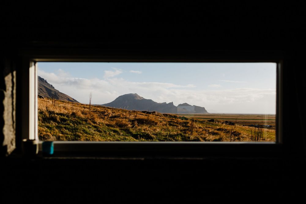 Rustic mountain landscape viewed through a narrow window frame at golden hour.