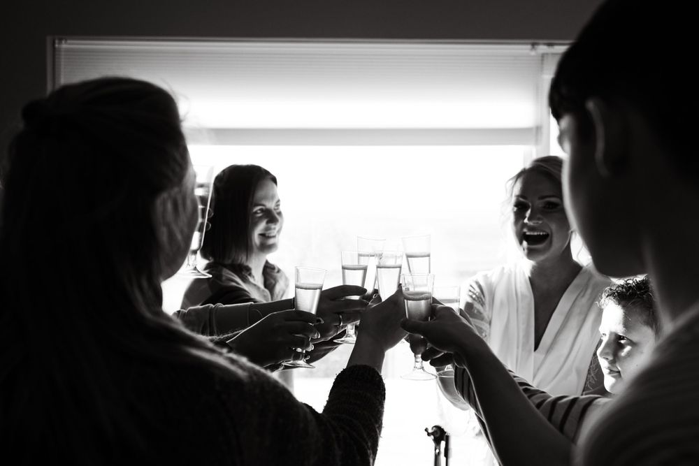 Black and white image of friends toasting with drinks in a celebratory moment.