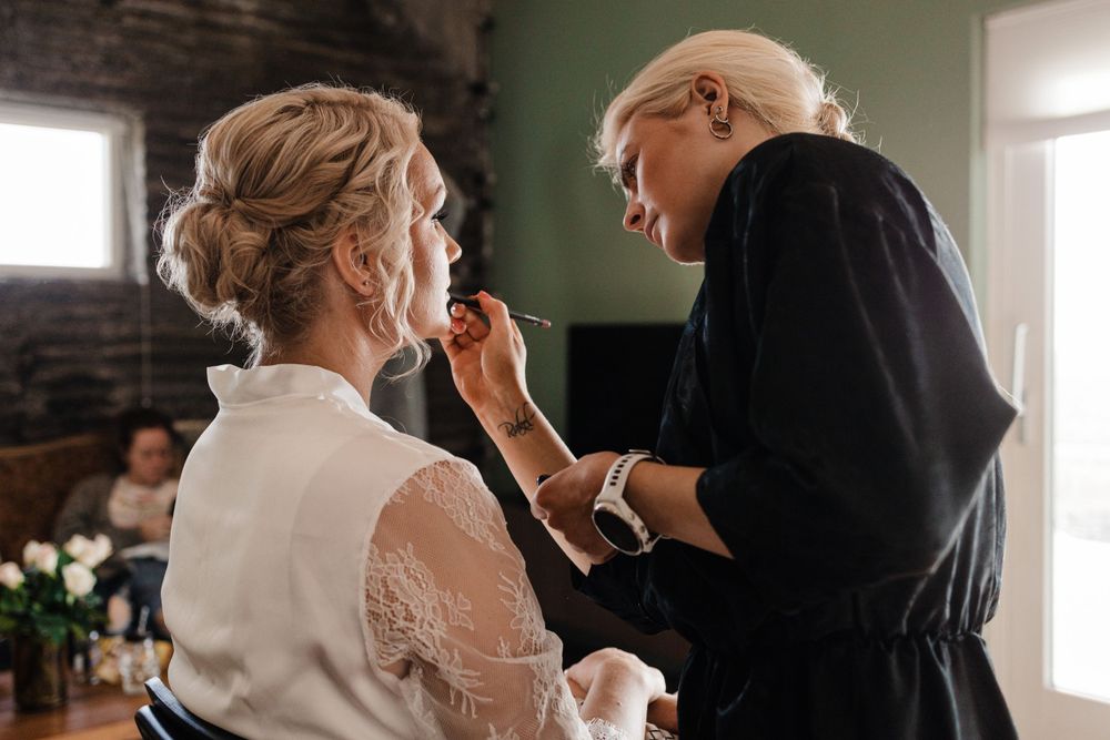 Wedding preparation scene showing final makeup touches being applied.
