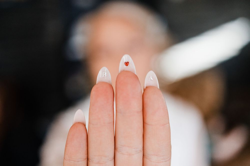 Close-up of freshly manicured white nails with rhinestone details.