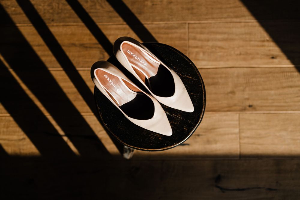 Black and white Oxford shoes on a circular black plate with dramatic shadows.