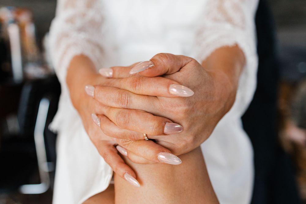 Close-up of clasped hands in white lace sleeves showing delicate details.