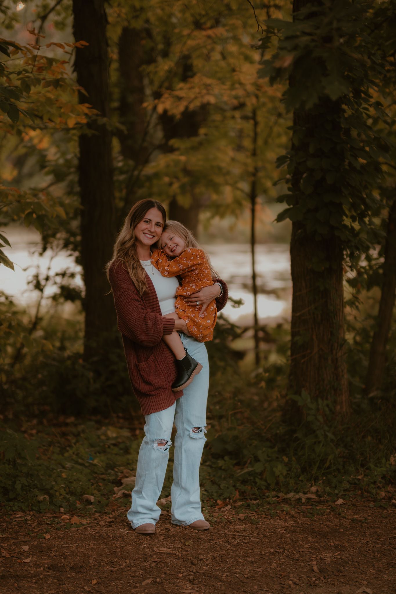 Autumn family portrait with matching burgundy sweaters against forest backdrop.
