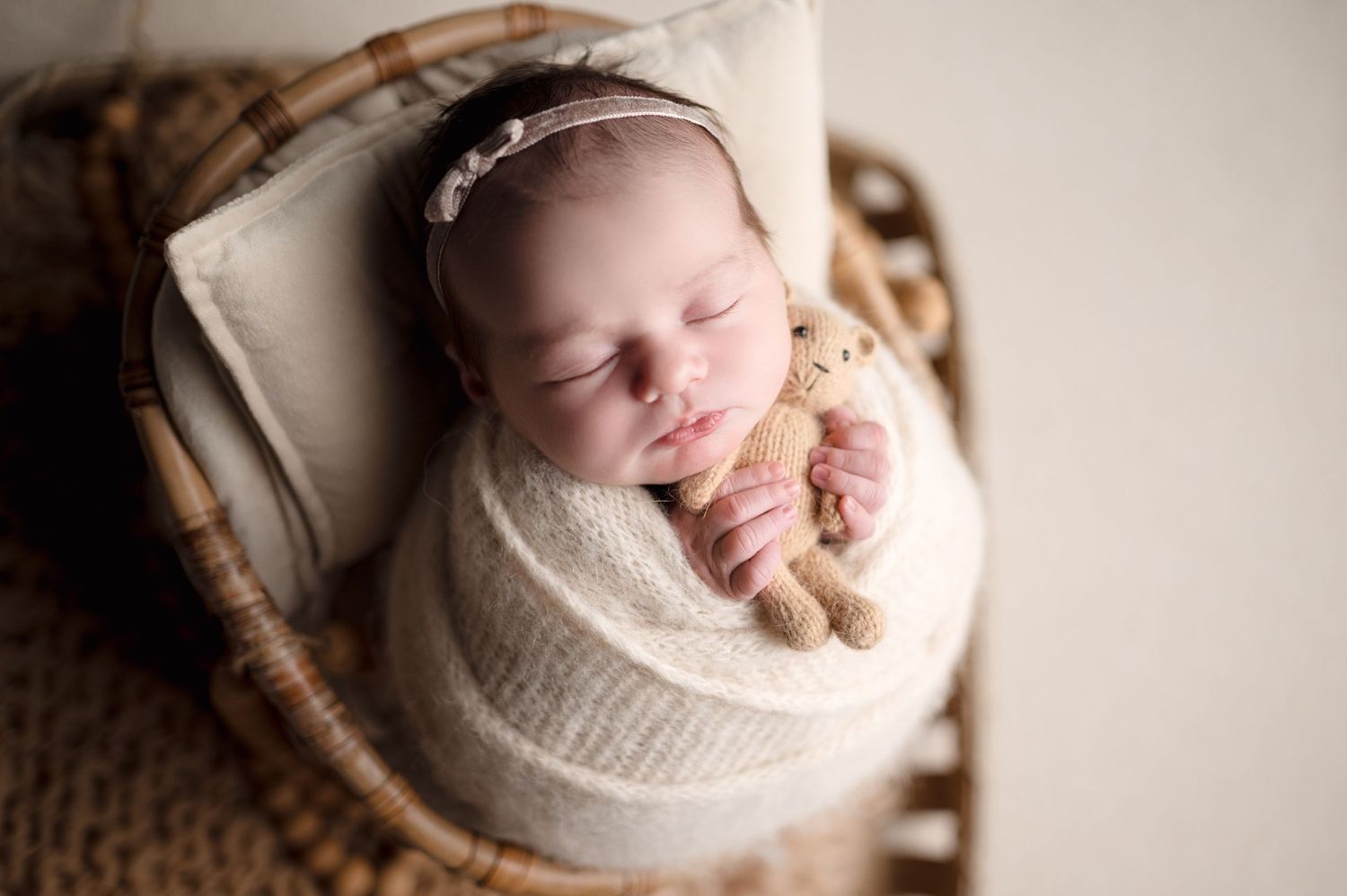 Artistic newborn portrait with soft focus and cream tones.
