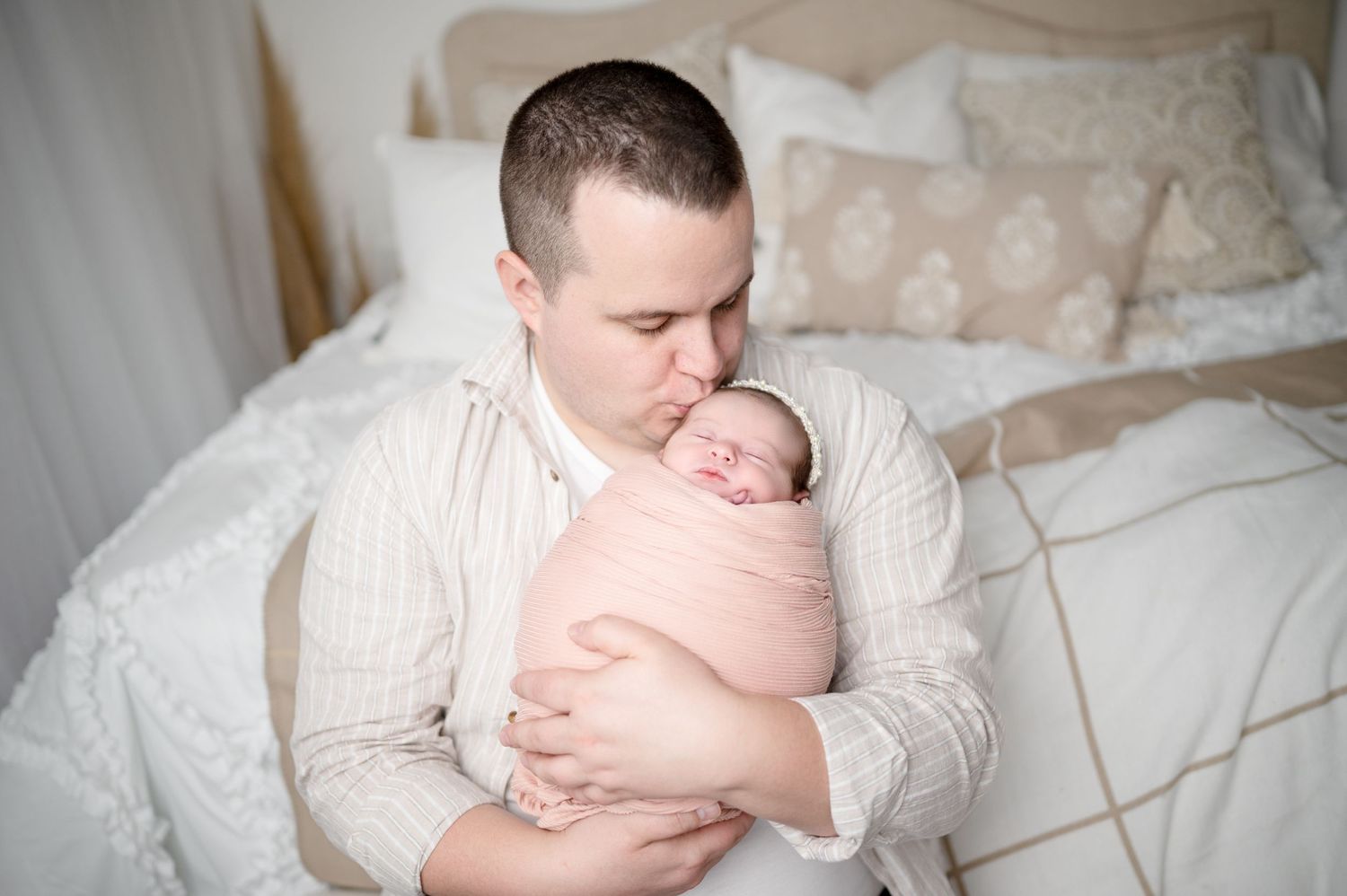 Parent lovingly gazing at newborn baby swaddled in pink blanket during intimate moment.