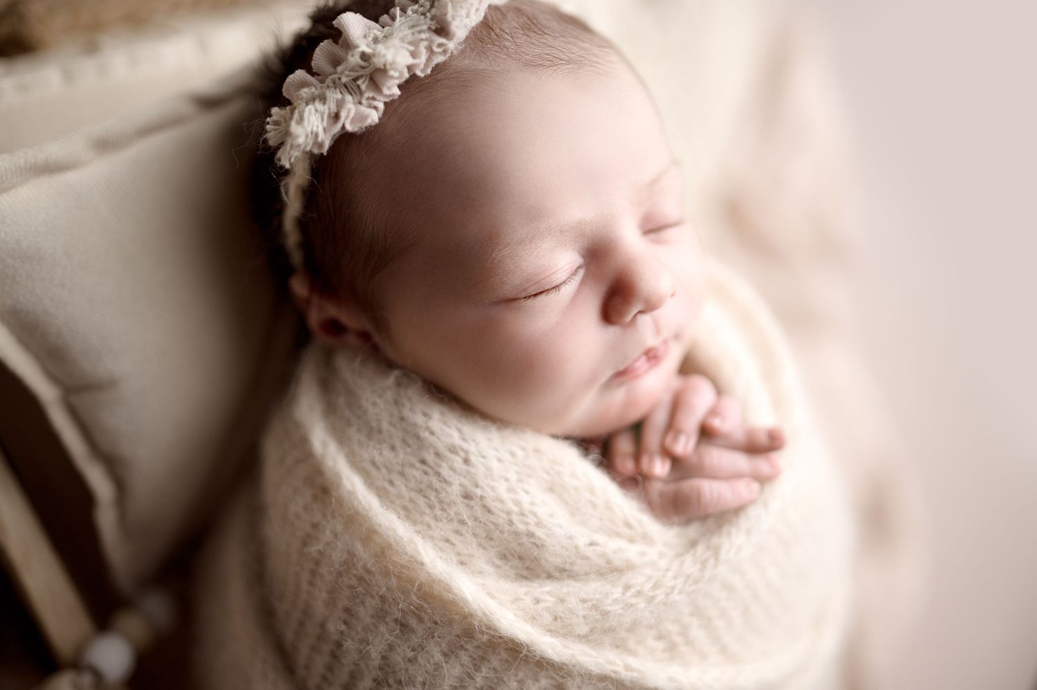 Close-up newborn portrait with delicate wrapping and soft lighting.