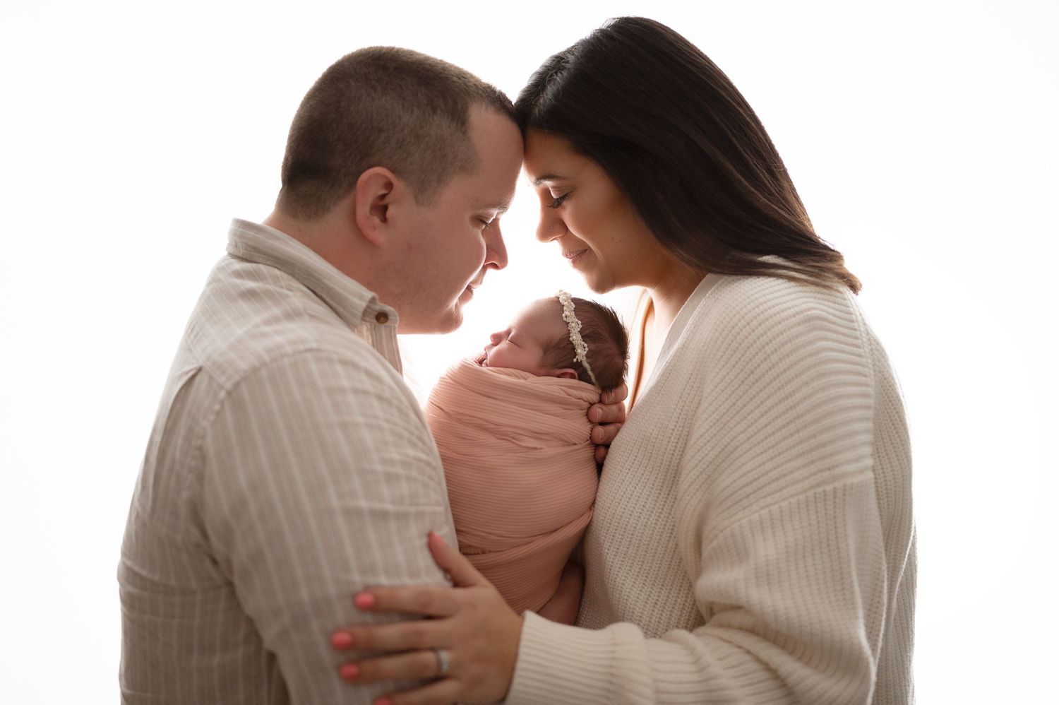 Parents sharing intimate moments with their newborn in studio portraits.