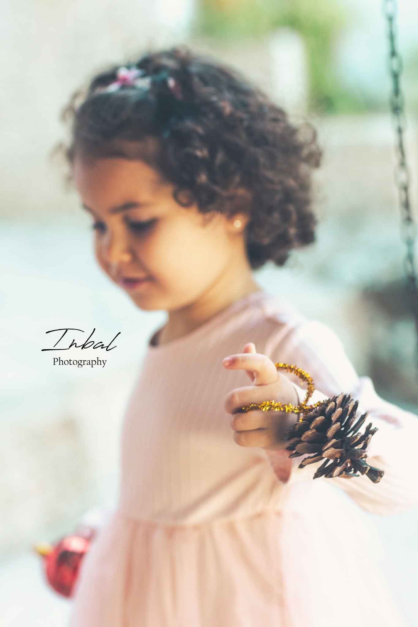Close-up of Lara's hand holding a pine cone Christmas decoration.